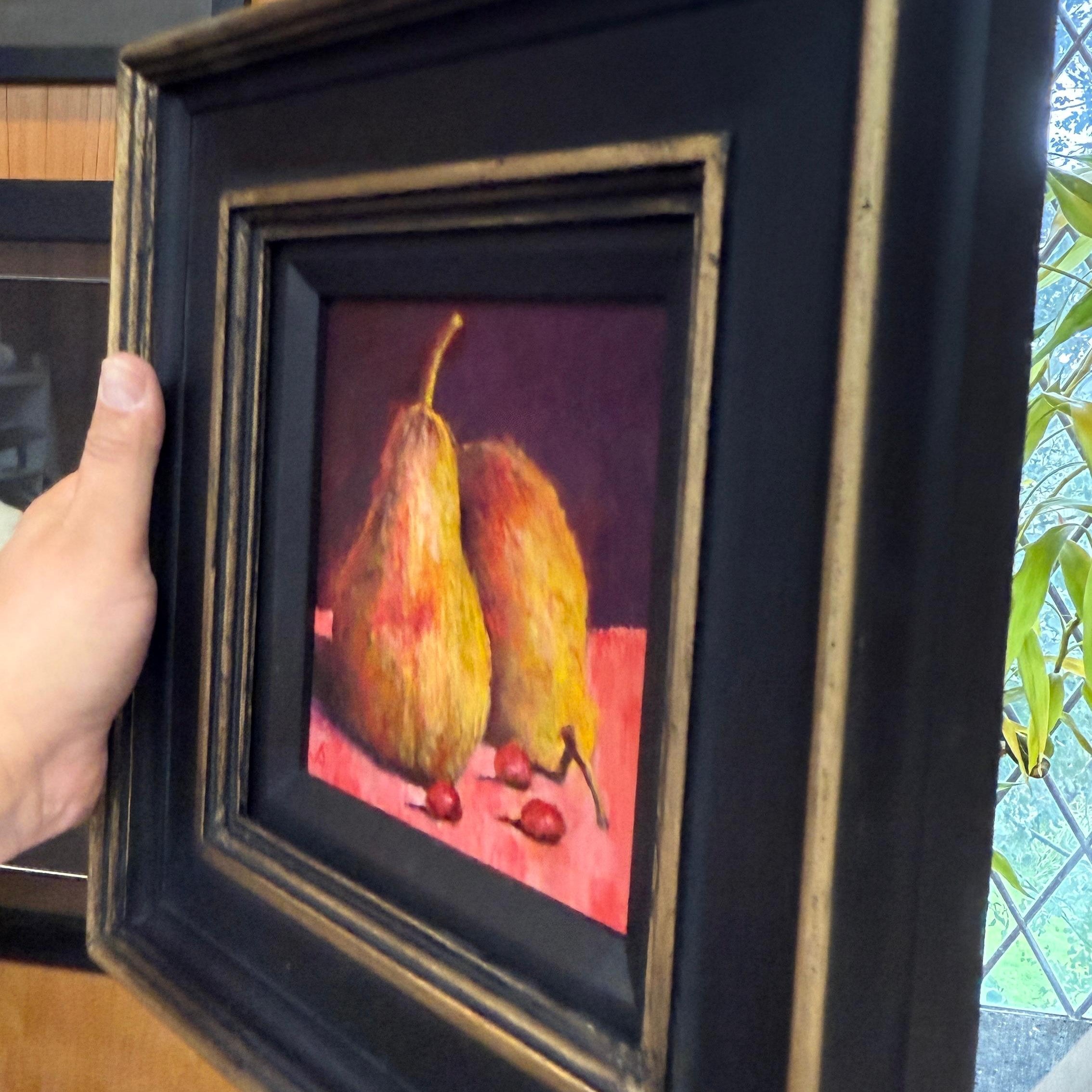 Framed painting of two pears on a red background held by a hand by Sarmed Mirza