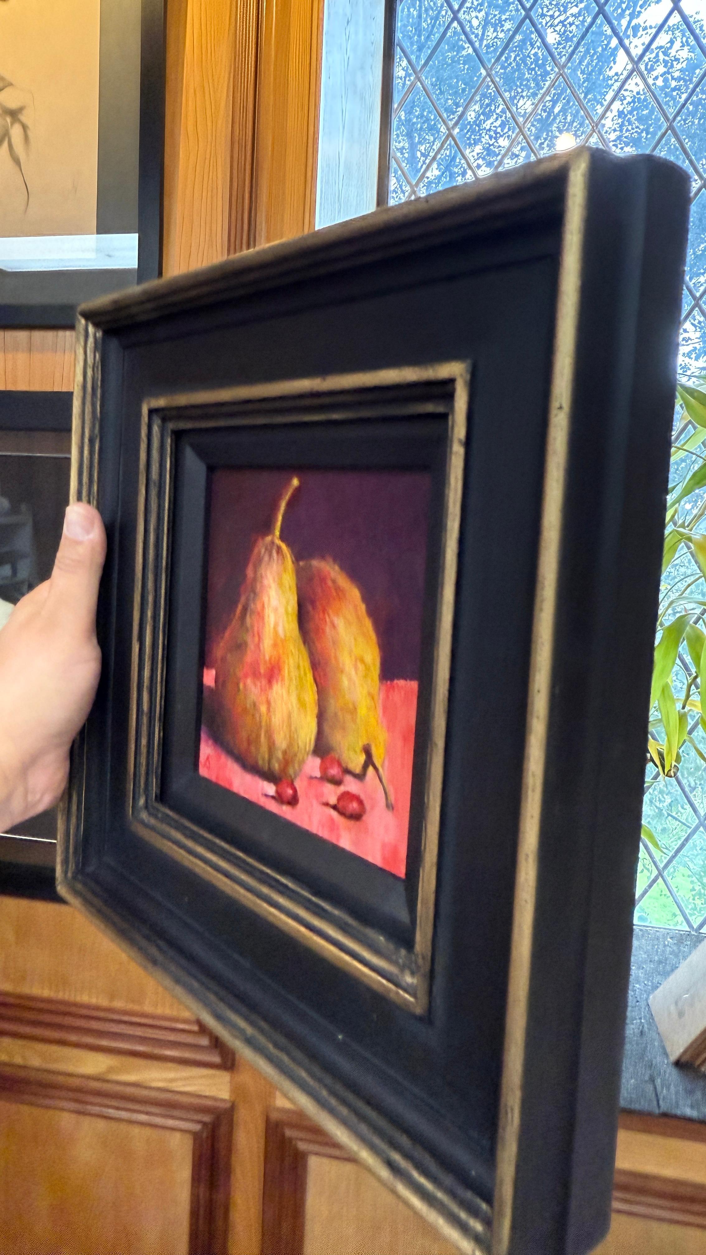 Framed painting of two pears on a red background held by a hand by Sarmed Mirza